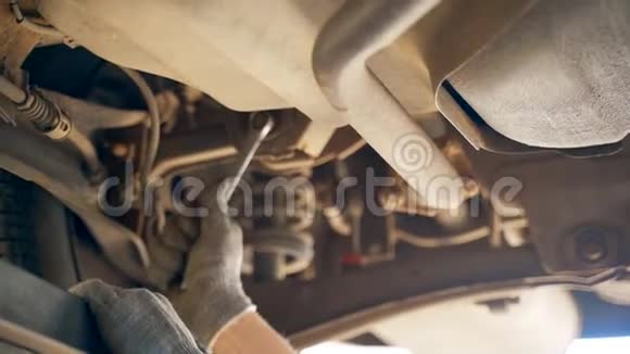 检查坑内一名汽车技工用扳手拧开汽车上的螺栓弯曲和脚趾的调整汽车视频的预览图