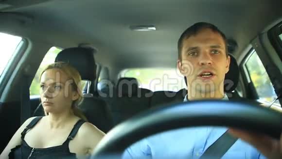 一对夫妇坐在车里一男一女一起坐在车里穿过城市的街道愉快地交谈着视频的预览图