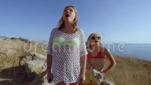 两个女孩背对着延伸大海的悬崖站着视频的预览图