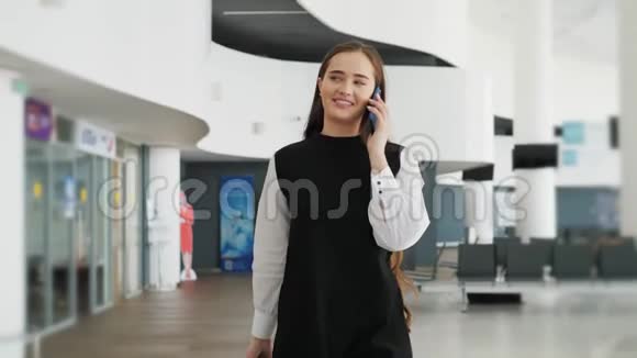 一位旅行商务女性在机场用手机说话的肖像带着手提箱的快乐学生在飞行中快乐地奔跑视频的预览图