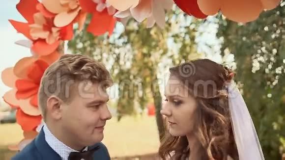幸福的新婚夫妇在浪漫的婚礼过道上亲吻装饰以鲜花的形式视频的预览图