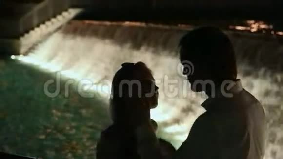 夜晚霓虹城背景1年轻情侣在户外拥抱相望的剪影视频的预览图