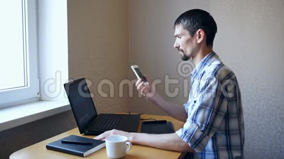 男人坐在笔记本电脑旁打电话视频的预览图