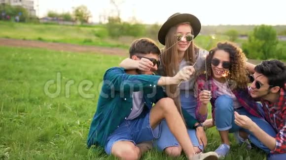 四个年轻的嬉皮士坐在草地上闪闪发光视频的预览图