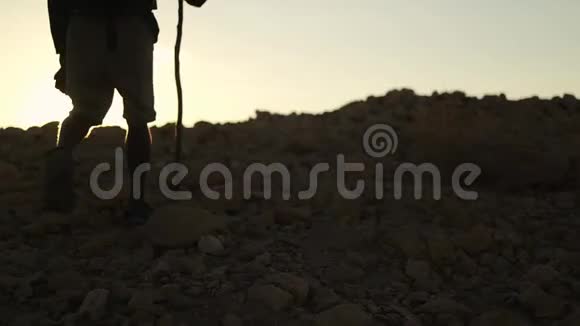 日落时分在沙漠中徒步旅行背包的深色皮肤旅行者视频的预览图
