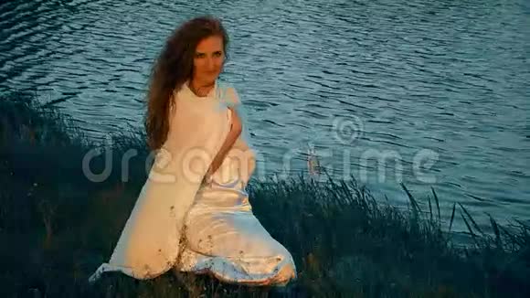 穿着白裙坐在河岸上的女人视频的预览图