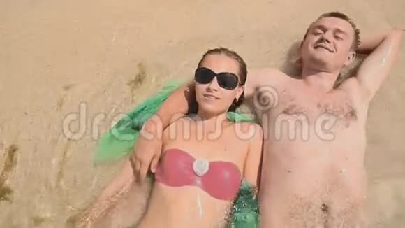 一对年轻夫妇躺在沙滩上视频的预览图