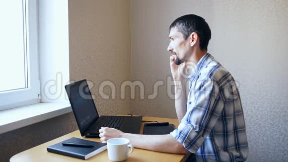 坐在笔记本电脑旁的男人在打电话视频的预览图