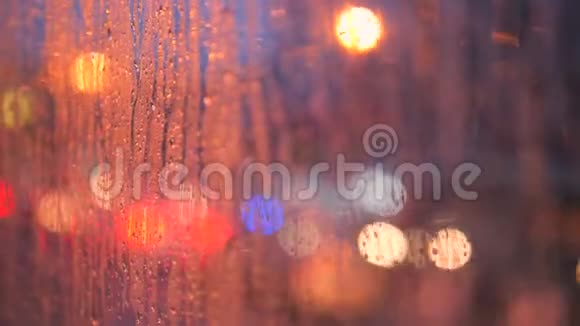 关闭车窗玻璃上的雨滴与模糊的夜间城市汽车灯博克作为背景4K视频的预览图