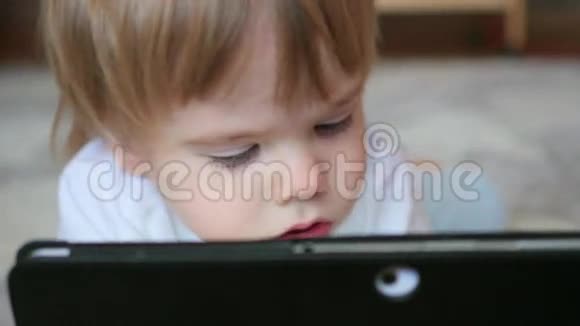 孩子们在平板电脑上看卡通在地板上看特写视频的预览图