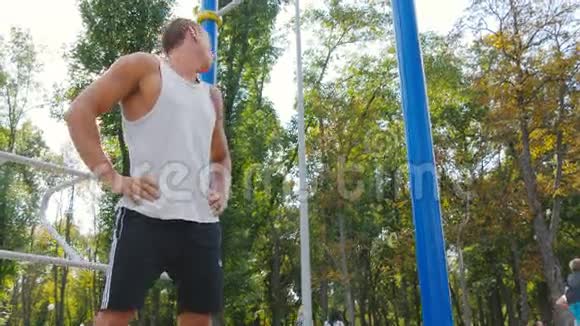 运动员在城市公园训练前热身他的脖子和头年轻强壮的肌肉男在锻炼前伸展身体视频的预览图