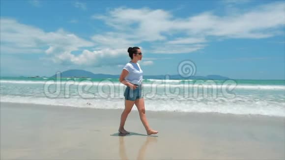 黑色眼镜白色衬衫和蓝色短裤的欧洲美丽的布鲁内特沿着炎热的夏季太阳走着视频的预览图