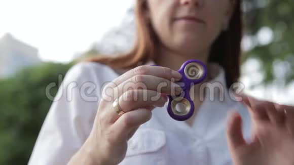 一个女孩正在玩一个旋转的玩具她的手在旋转那个女孩在露天旋转旋转视频的预览图