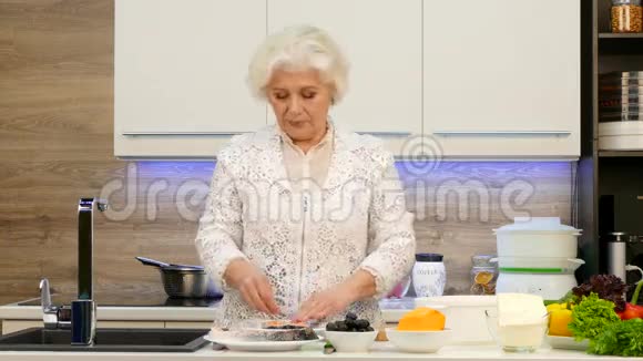 家庭主妇养老金领取者准备膳食晚餐一对烤鳟鱼和蔬菜装饰视频的预览图