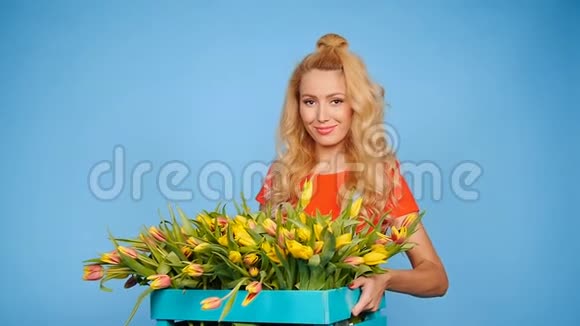 年轻的金发女郎蓝色背景的郁金香视频的预览图