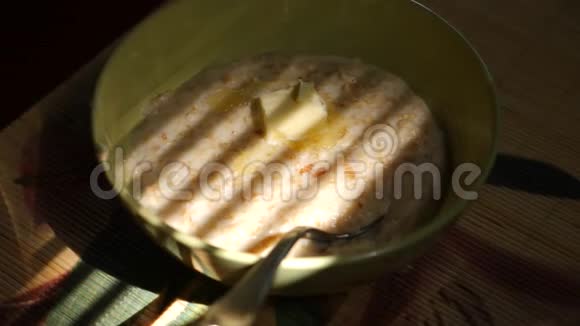 加燕麦片和融化黄油的盘子在百叶窗阴影的背景下在家吃早餐4k慢视频的预览图