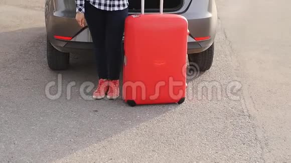 一位年轻的女旅行者她的车旁边放着一个手提箱视频的预览图