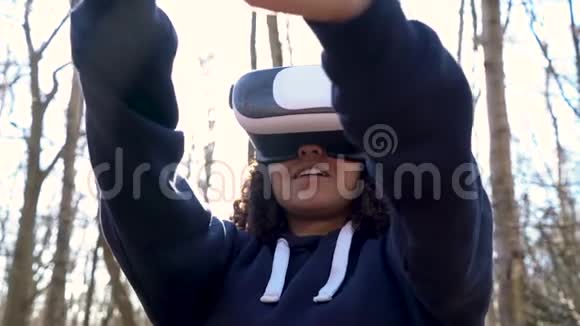 在森林林地环境中使用虚拟现实VR耳机的非裔美国少女女青年视频的预览图