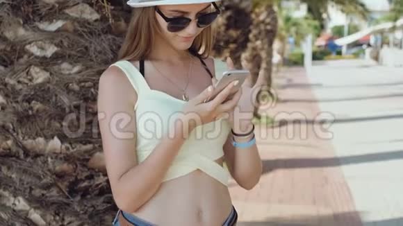 在炎热的夏日里时尚女孩用手机在街上自拍视频的预览图