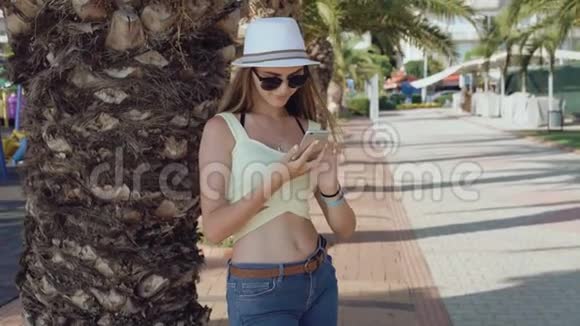 在炎热的夏日里时尚女孩用手机在街上自拍视频的预览图