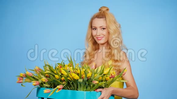 年轻的金发女郎蓝色背景的郁金香视频的预览图