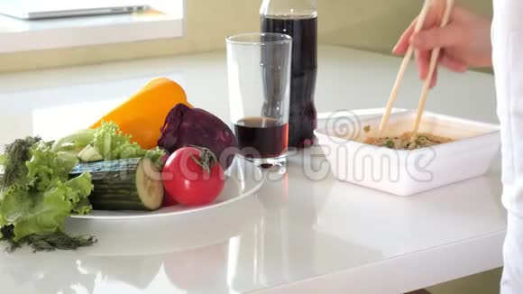 一个女人坐在桌子旁吃中国面条和新鲜蔬菜视频的预览图