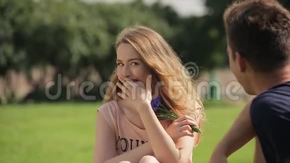 活泼可爱的女孩坐在草坪上和她的男朋友在邋遢中聊天视频的预览图