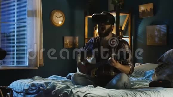 晚上在床上戴着虚拟现实眼镜弹吉他的男人视频的预览图