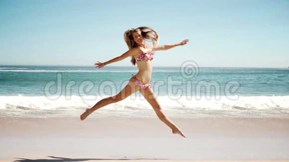 快乐的年轻女子在沙滩上跳着电影视频的预览图