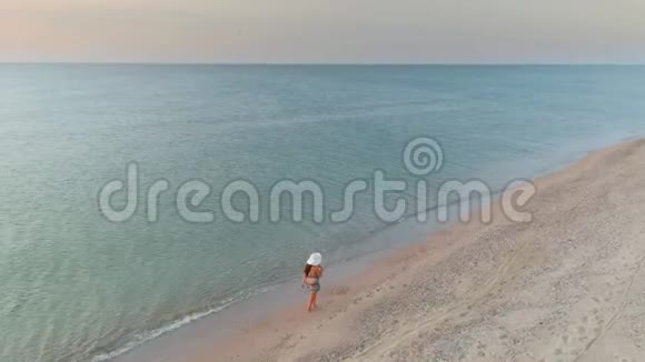 日落时分一位女士在海边散步的美丽景色视频的预览图