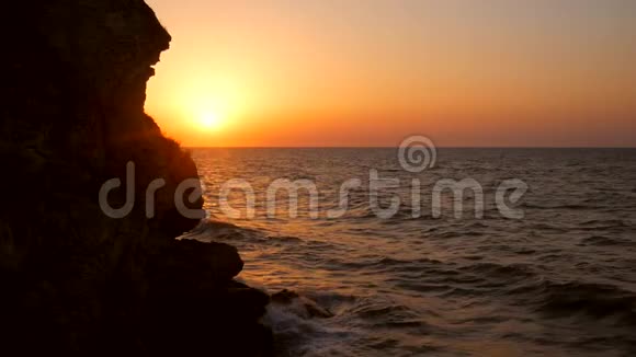 海滩上的日出在海上迎着金色的日落波浪在石头上慢慢飞溅高清慢速运动克里米亚a视频的预览图