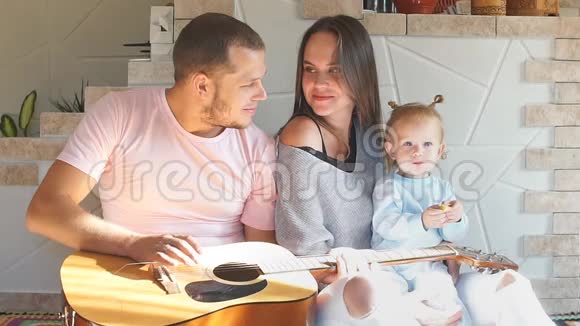 漂亮的年轻家庭花时间在厨房父亲弹吉他视频的预览图