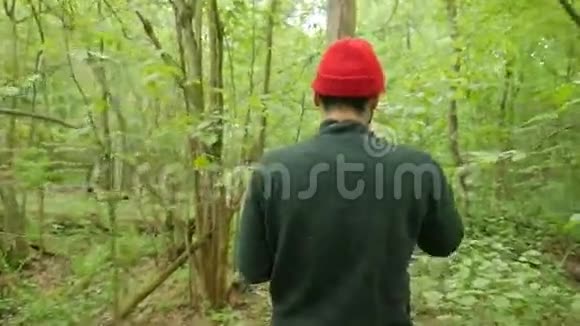 年轻的旅行者在森林里散步徒步穿越绿色公园徒步旅行者的后景高加索混血视频的预览图