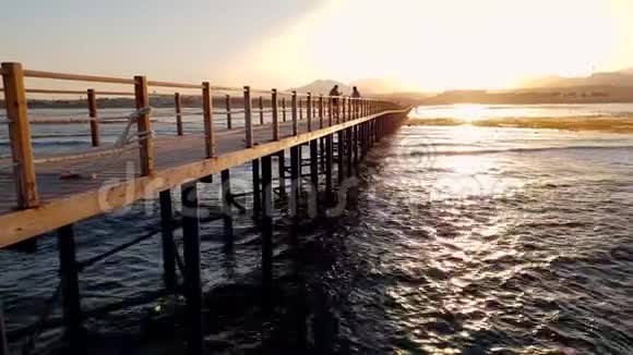 日落时分美丽的长木码头在海上的4k镜头视频的预览图