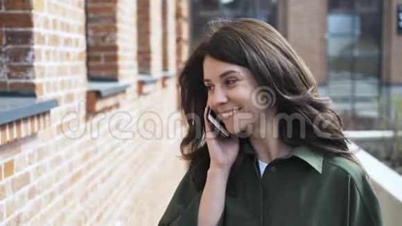 穿绿色衬衫的可爱女孩在街上打电话视频的预览图