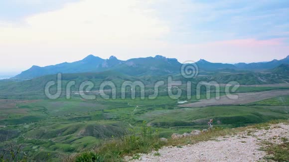 一个游客骑着运动自行车开车到山顶有山谷和大海的景色视频的预览图