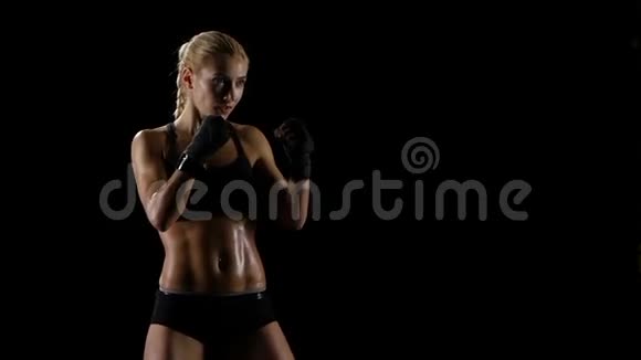 女运动员在黑暗的工作室里打拳击慢动作视频的预览图