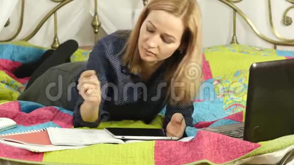 友好的女学生躺在床上看数字平板电脑美丽的女人在家里在线教育4K视频的预览图