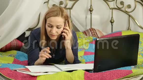 学生躺在家里的床上在笔记本电脑上工作的女人在线教育慢动作视频的预览图