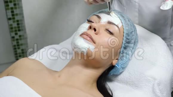 女性美容师为美容中心的女性客户制作化妆品面膜接近漂亮的高加索人视频的预览图