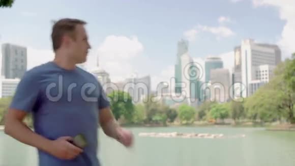 男跑运动员在公园慢跑适合男性运动健身训练在他的智能手机上拍照视频的预览图