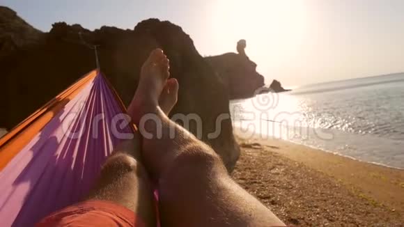 年轻人躺在沙滩上的吊床上欣赏海边美丽的日落1920x1080慢动作视频的预览图