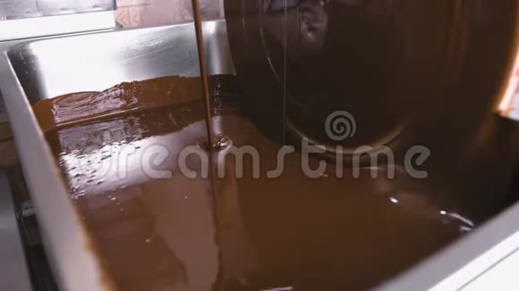 巧克力回火机中的温液巧克力特写镜头巧克力糖果的生产视频的预览图