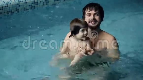 父亲和儿子在游泳池里年轻的爸爸教他3岁的儿子游泳视频的预览图
