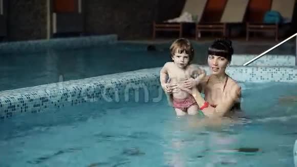 在游泳池里的母子年轻的母亲教她3岁的儿子游泳视频的预览图