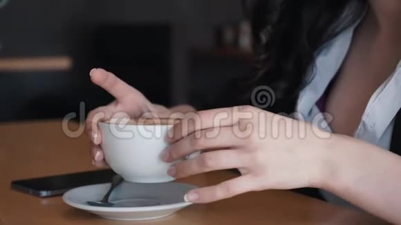 美丽的黑发女孩在餐馆喝咖啡享受味道和香气视频的预览图