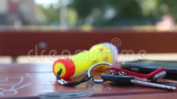 钥匙智能手机和手电筒钥匙链在室外桌子上视频的预览图