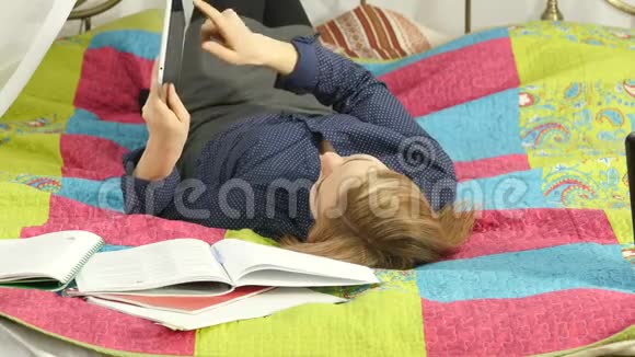 友好的女学生躺在床上看数字平板电脑美丽的女人在家里在线教育4K视频的预览图