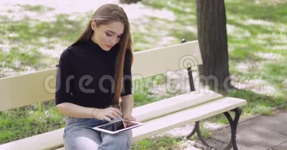 开朗的年轻女人在外面用平板电脑视频的预览图