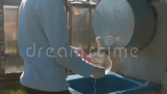 女人在户外的自制水槽里洗了一个碗双手特写视频的预览图